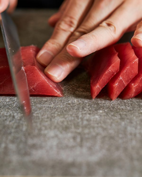 Sushi chef hand-forming nigiri at a live chef experience station